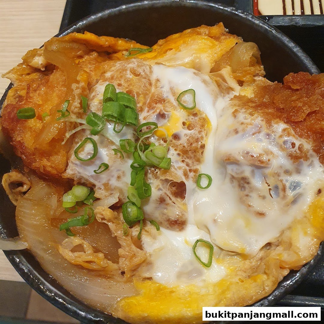 A close-up of a delicious Japanese katsudon dish with fried pork, egg, and onions.