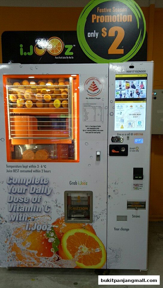 A vending machine dispensing fresh fruit juice, featuring oranges and a festive promotion.