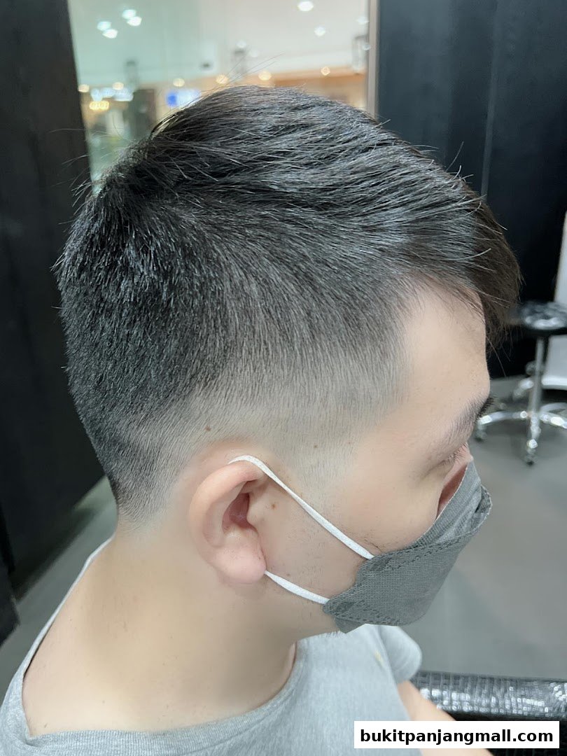A close-up of a man's head with a fresh haircut and a grey face mask.