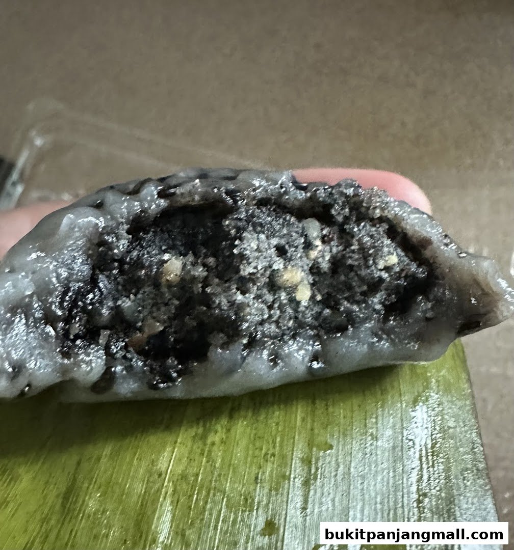 A close-up of a black sesame Ang Ku Kueh, sliced open, revealing its filling.