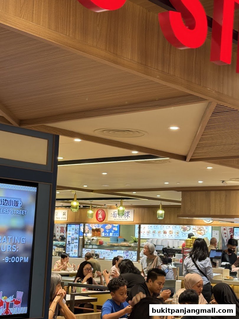 People dining at a food stall with a menu display and signage.