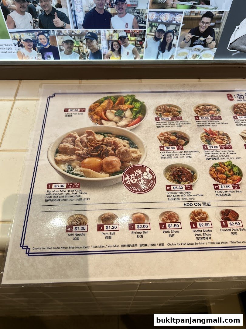 A menu board displaying various noodle dishes and add-on options with prices.