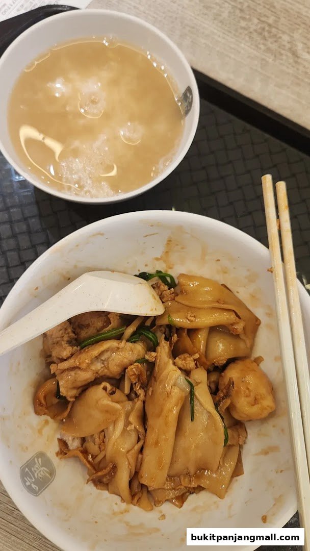 A bowl of Mee Hoon Kway with soup and chopsticks, ready to be eaten.