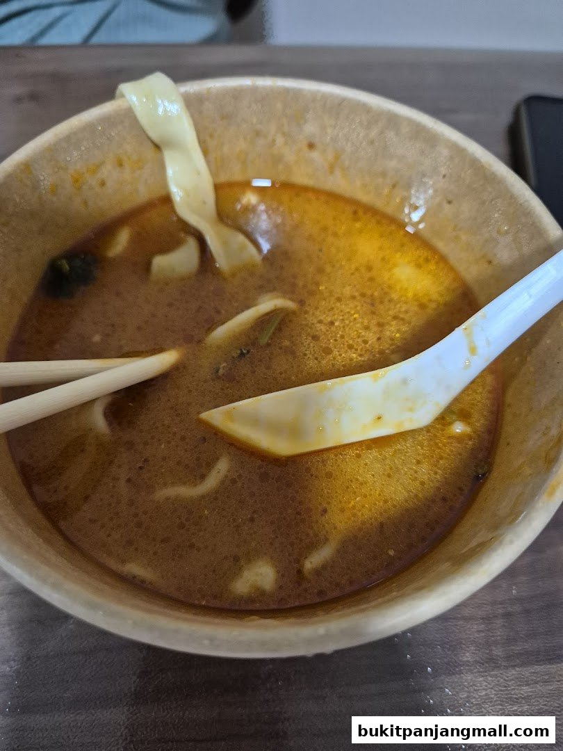 A close-up shot of a bowl of Mee Hoon Kway with chopsticks and a spoon.