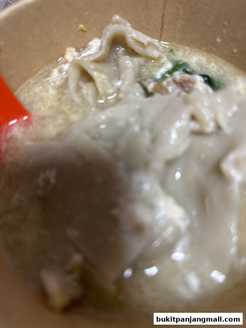 A close-up shot of a bowl of Mee Hoon Kway with a red spoon.