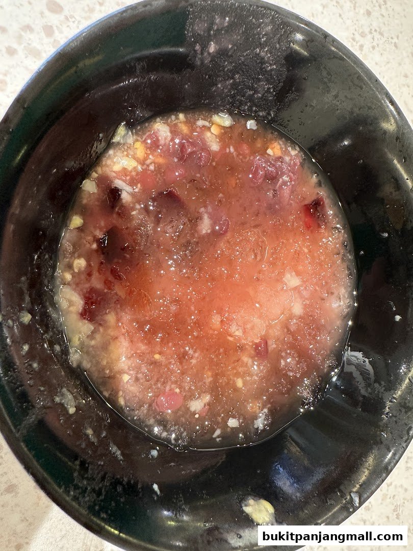 A close-up shot of a bowl filled with a pinkish, icy dessert with fruit pieces.
