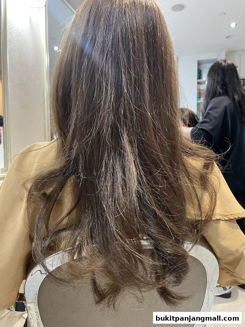 A woman's long, brown, wavy hair is styled in a salon.