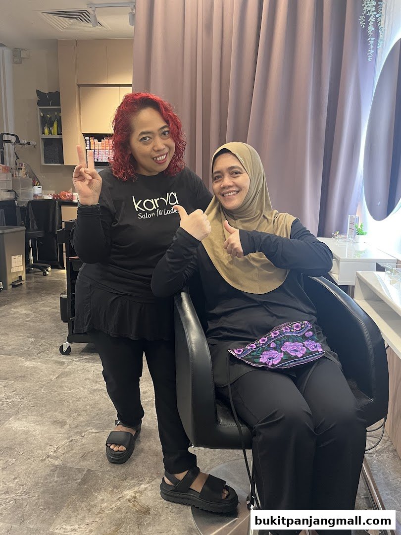 Two smiling women, one in a KARVA Salon t-shirt, pose for a photo inside the salon.
