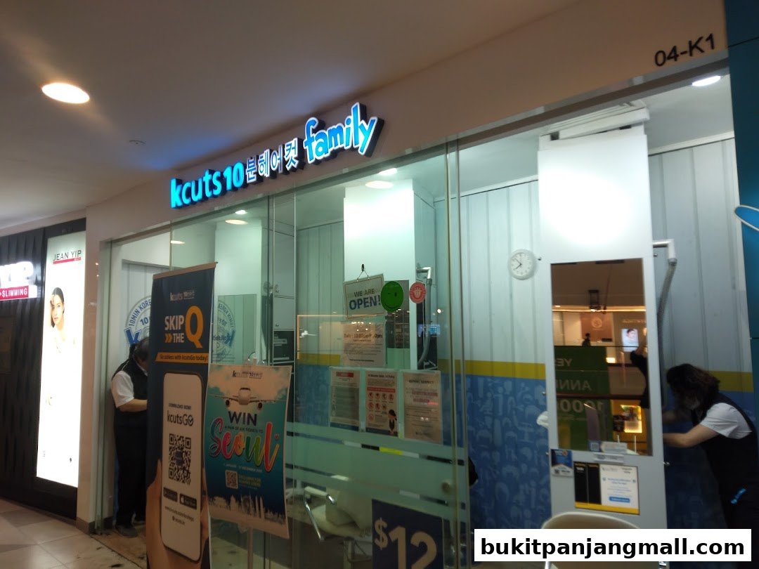 The storefront of a kcuts hair salon with bright signage and promotional posters.