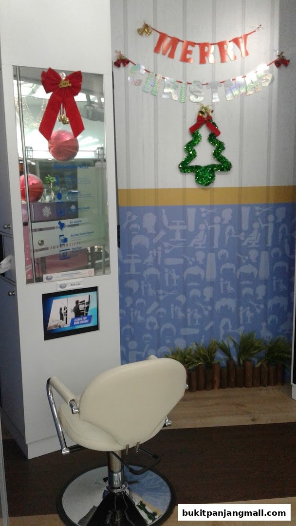 A salon chair sits in front of a wall decorated with Christmas banners and a festive tree.