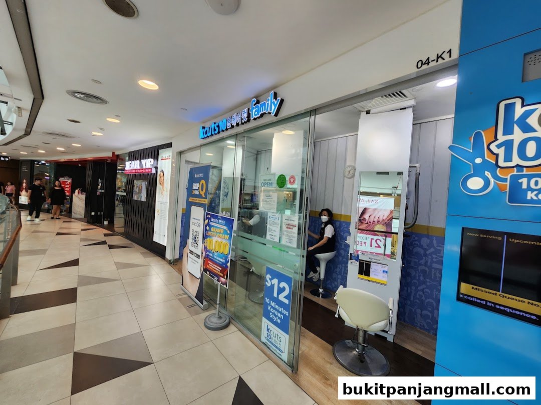 The exterior of a kcuts hair salon with a stylist inside and a promotional poster.