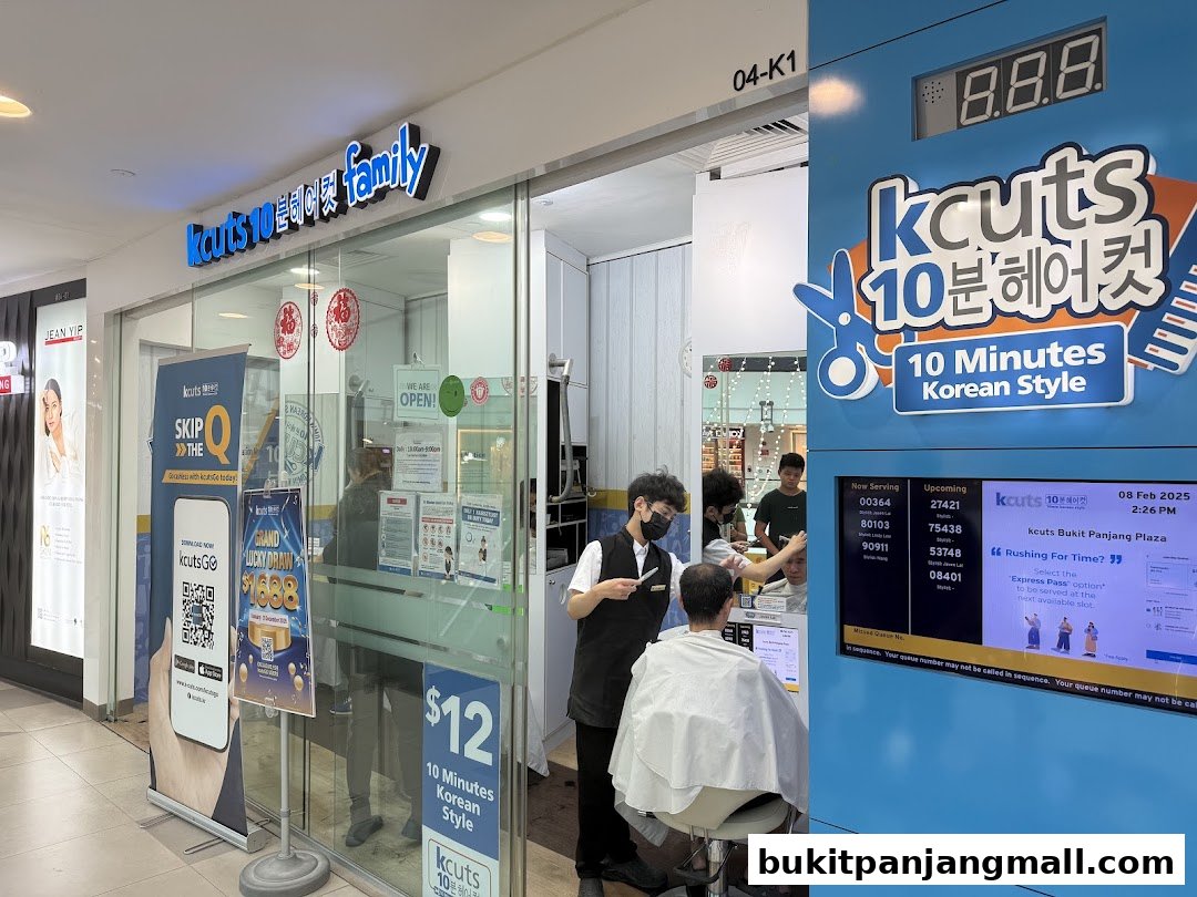 A kcuts hair salon with staff cutting a customer's hair and a digital queue display.