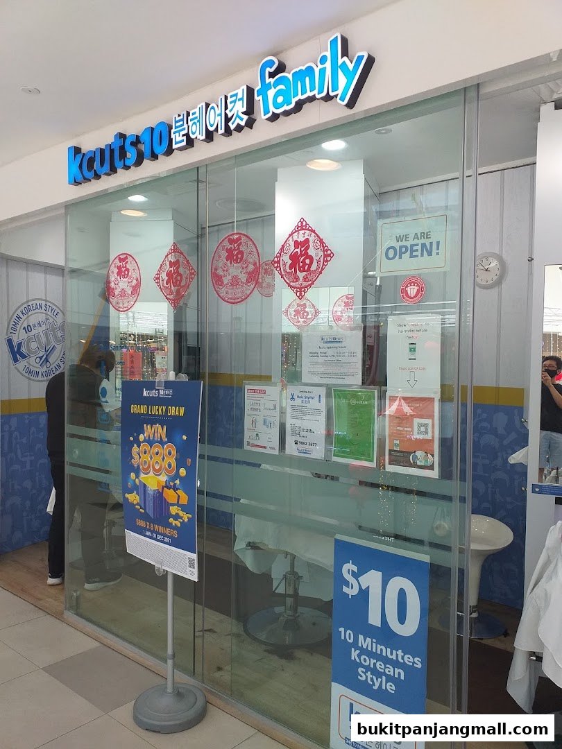 The storefront of Kcuts hair salon, featuring a bright sign and promotional posters.