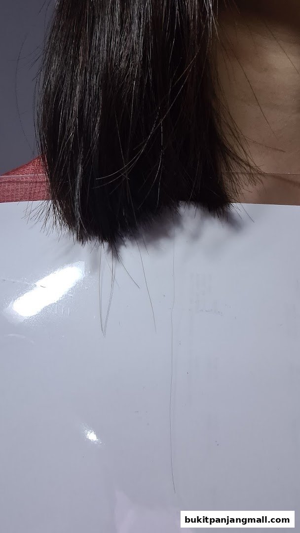 A close-up shot of a person's dark hair being held against a white surface.