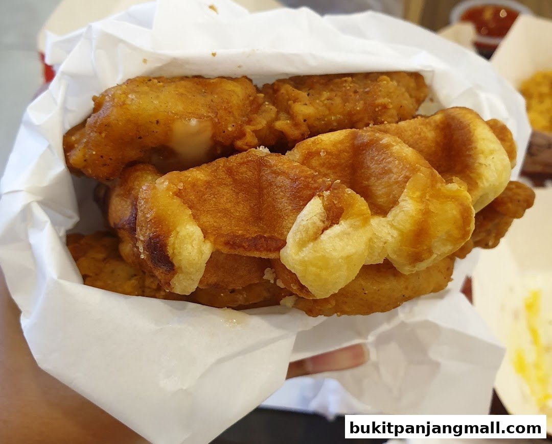 A close-up shot of crispy fried chicken pieces layered with golden waffles.