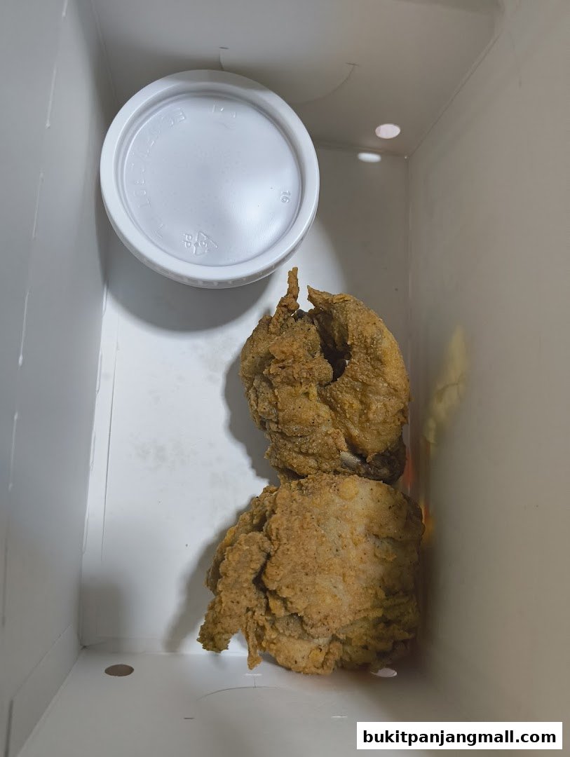 A box of crispy fried chicken pieces with a white lid.