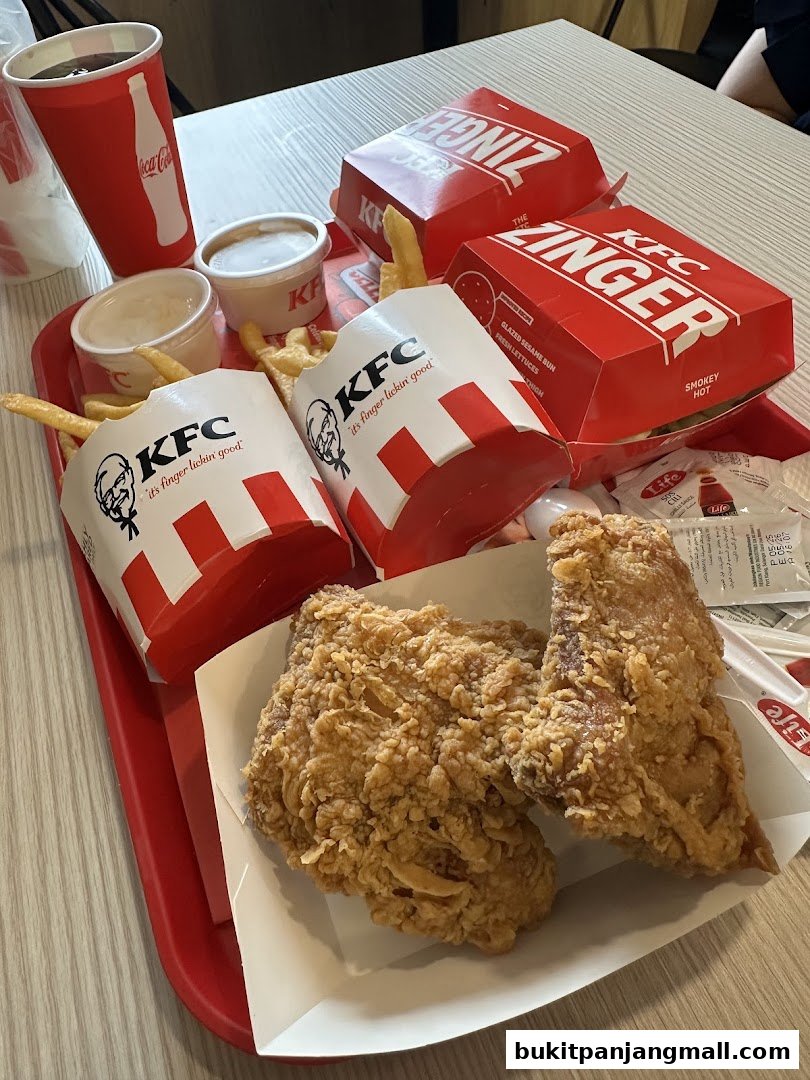 A tray of KFC fried chicken, Zinger burgers, fries, and drinks on a table.