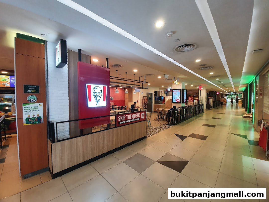 The exterior of a KFC restaurant with its iconic logo and seating area visible.
