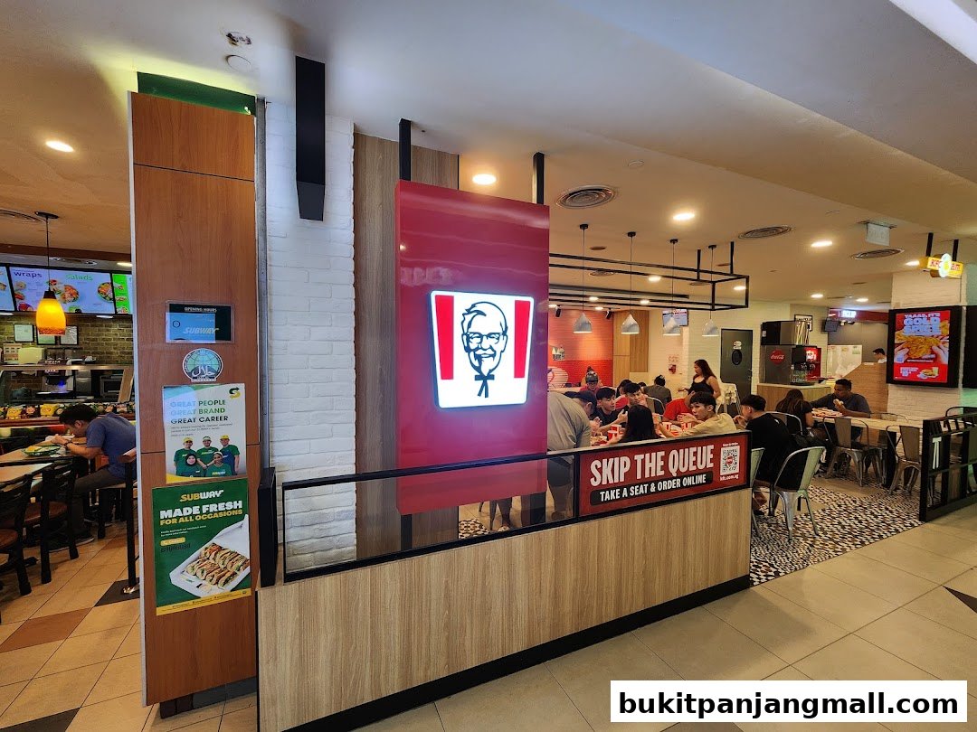 Interior view of a KFC restaurant with customers dining and a Subway outlet visible.