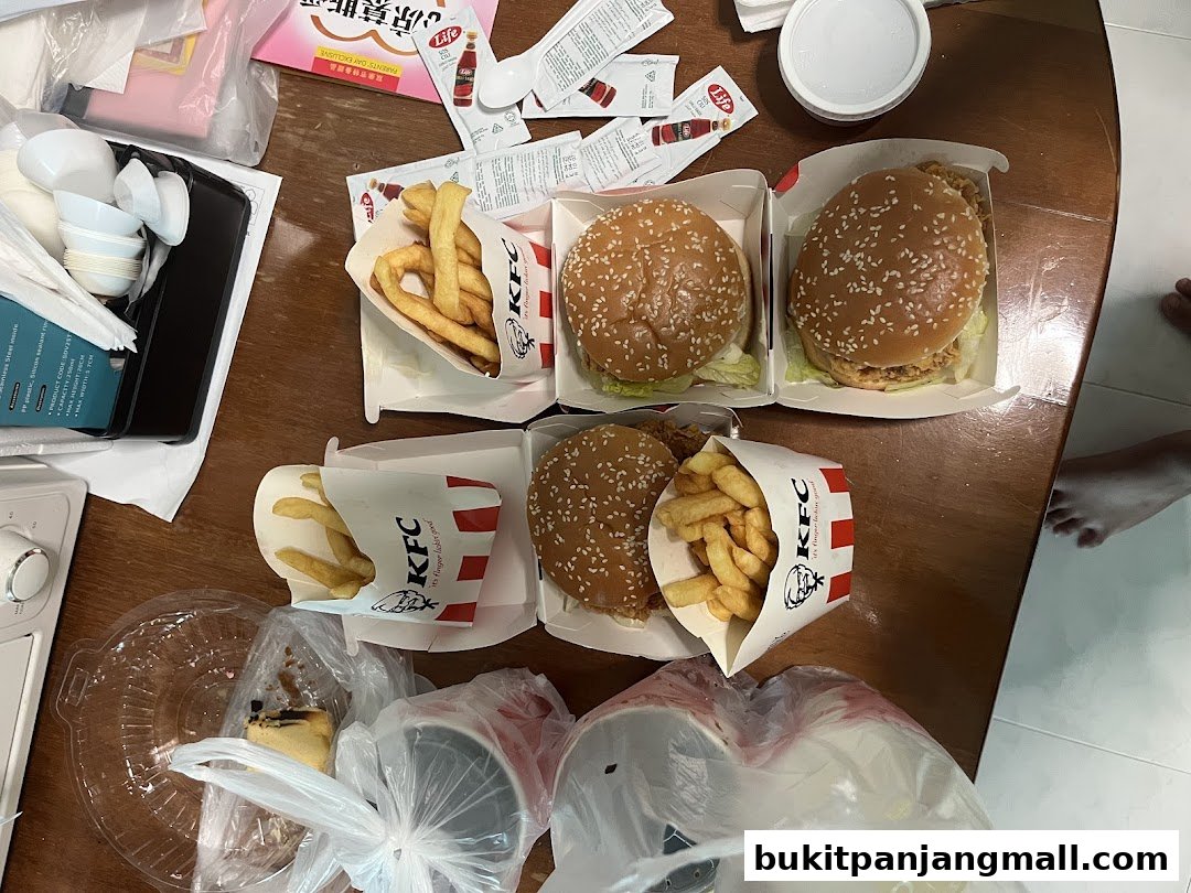 A table laden with KFC burgers, fries, and drinks, suggesting a meal.