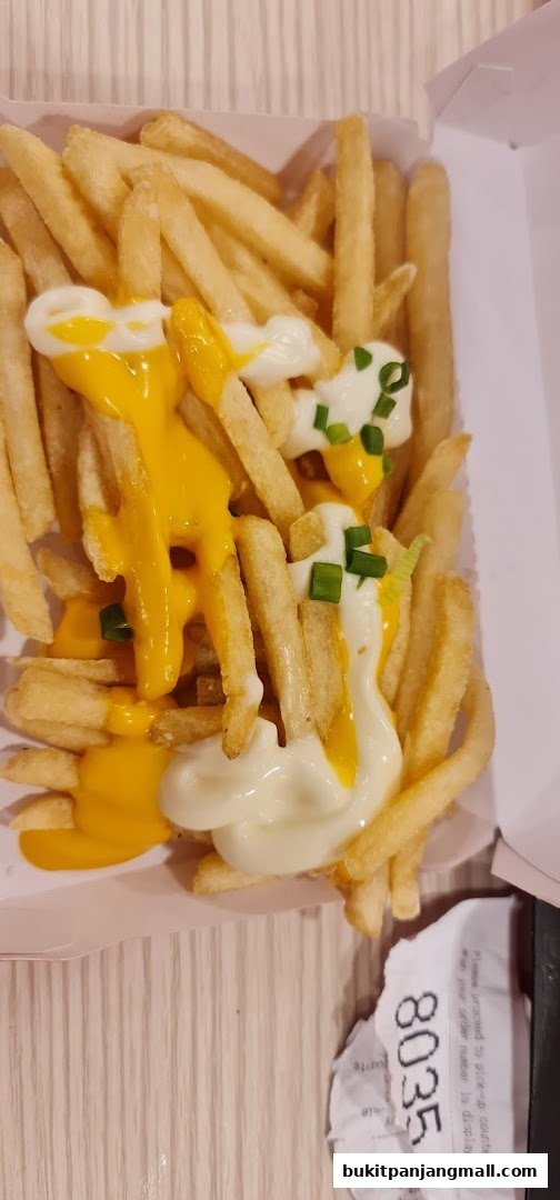 A box of crispy french fries topped with cheese sauce, mayonnaise, and chives.
