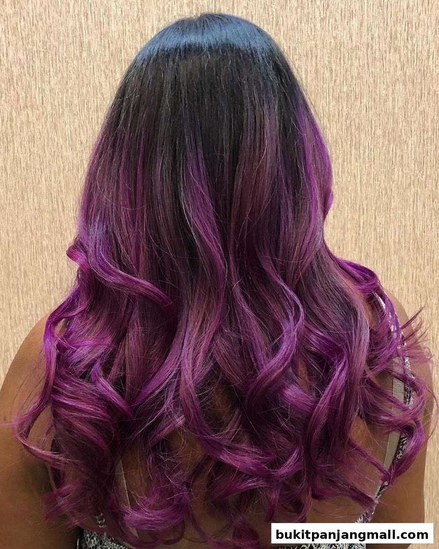A person's back with long, wavy hair colored in a gradient of black to vibrant purple.