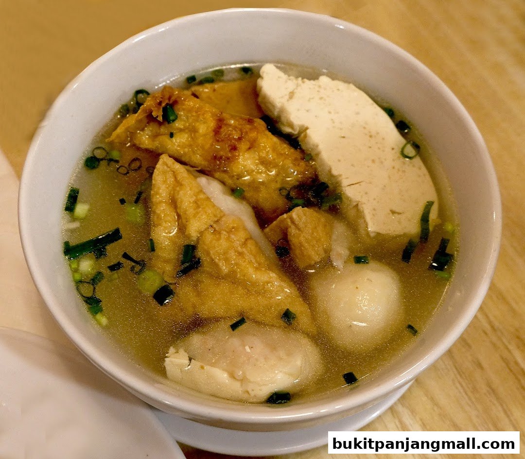 A close-up shot of a steaming bowl of soup with various ingredients like tofu and meatballs.