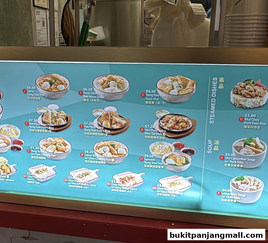 A brightly lit menu board displaying various noodle and soup dishes with accompanying images.