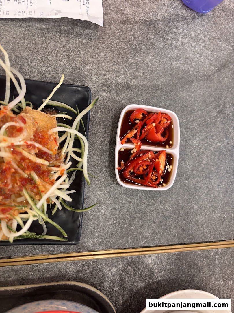 A close-up of a dish with shredded vegetables and chili sauce at Koo Kee.