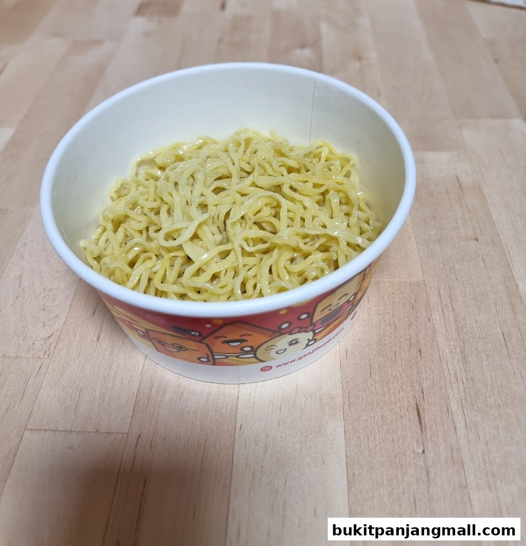 A bowl of delicious-looking noodles with a cartoon-decorated paper container.