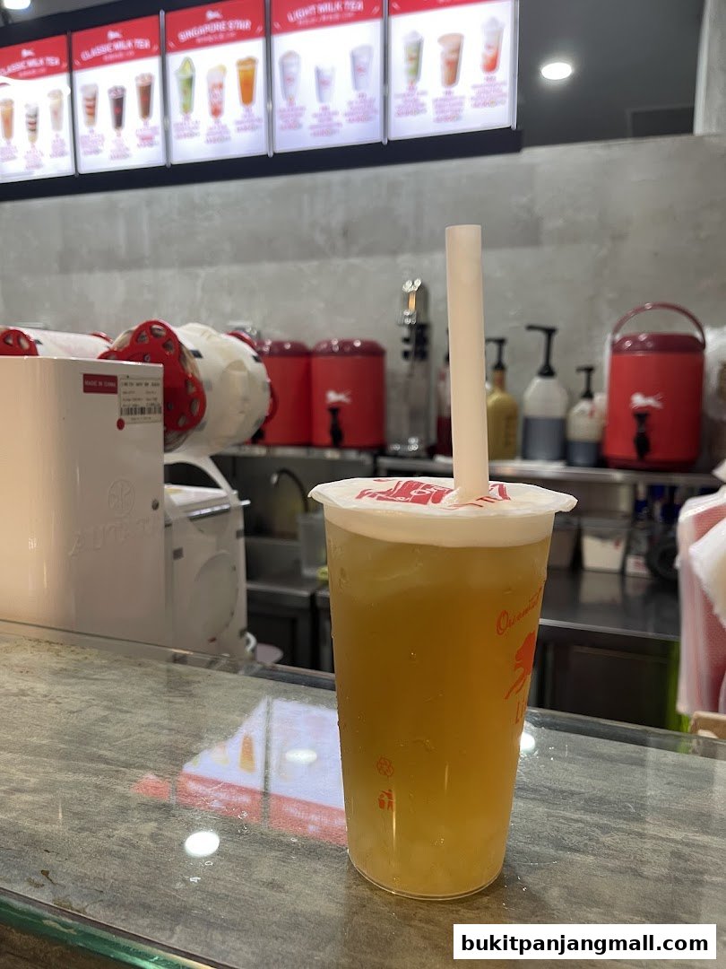 A refreshing LiHO TEA drink with a menu board displaying various milk teas in the background.