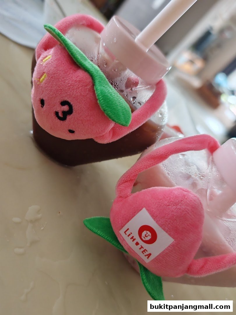 Two LiHO TEA drinks with cute pink strawberry-themed plush charms and straws.
