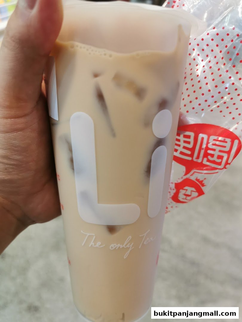 A hand holds a LiHO TEA cup with ice and milk tea.