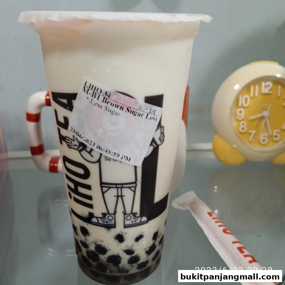 A cup of LiHO TEA brown sugar milk tea with boba and a straw.