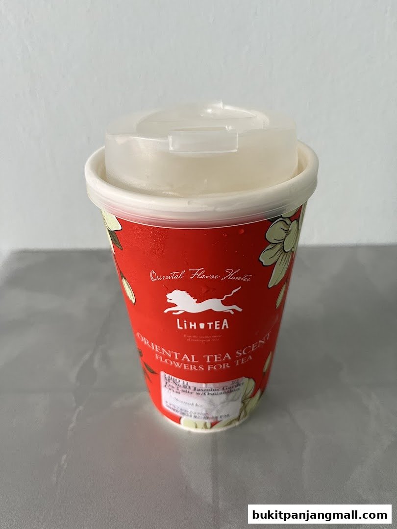 A red LiHO TEA cup with a white lid, featuring floral designs and branding.