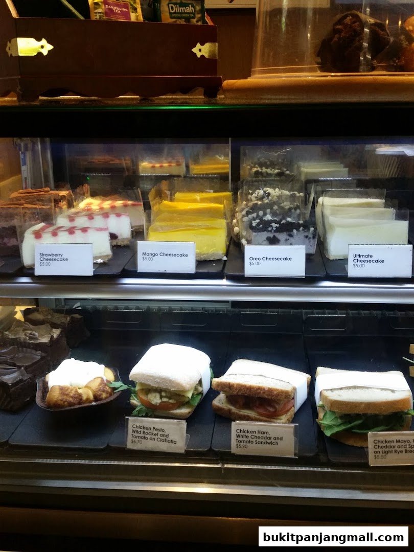 A display case filled with various cheesecakes and sandwiches.