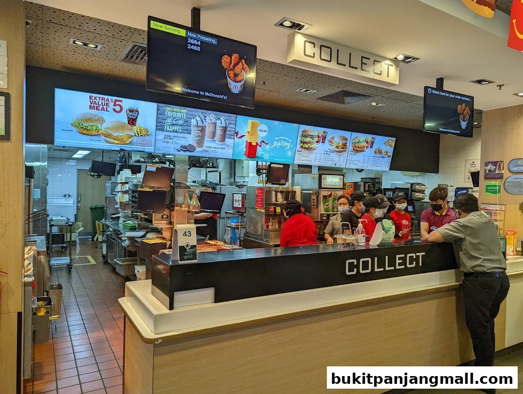 McDonald's counter with staff serving customers and digital menu boards displaying food items.