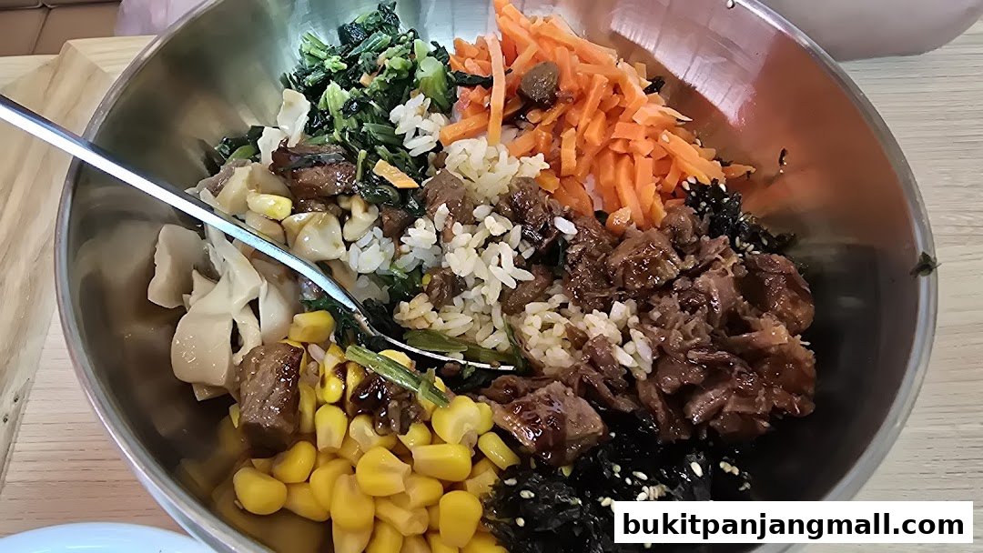 A close-up of a delicious bibimbap served in a metal bowl with a fork.