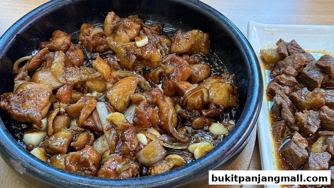 A close-up of two Korean dishes: one with glazed chicken and onions, the other with braised beef.