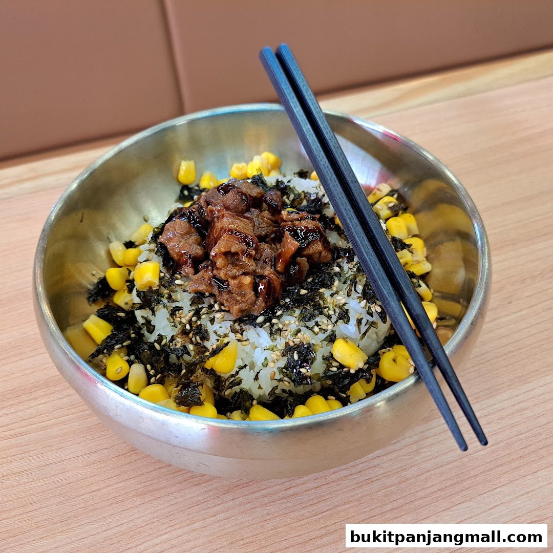 A close-up of a Korean bibimbap dish with beef, corn, seaweed, and sesame seeds.