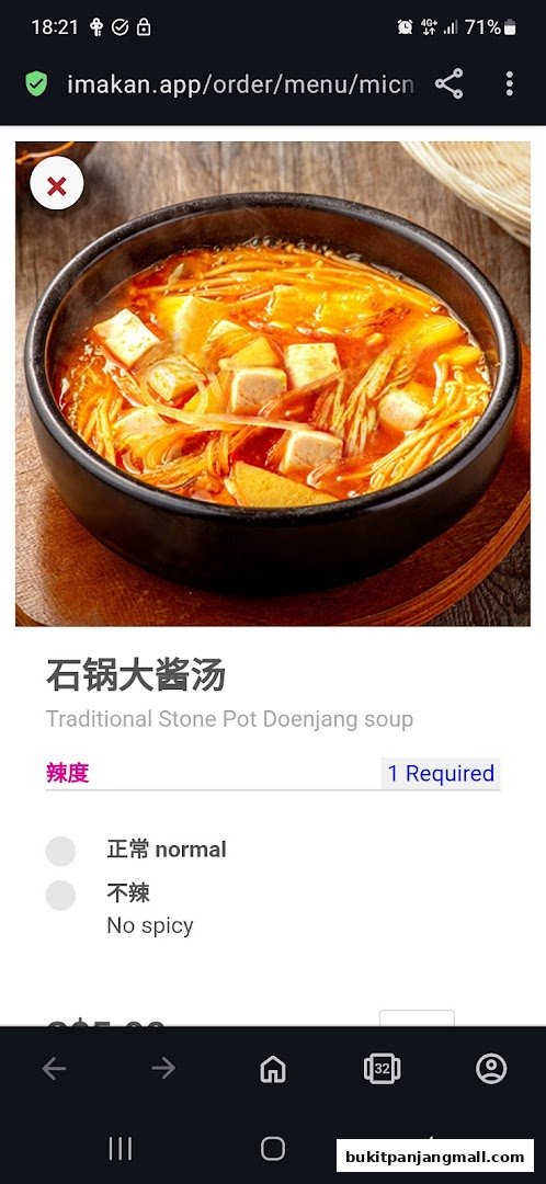 A close-up of a steaming bowl of traditional Korean Doenjang soup with tofu and enoki mushrooms.