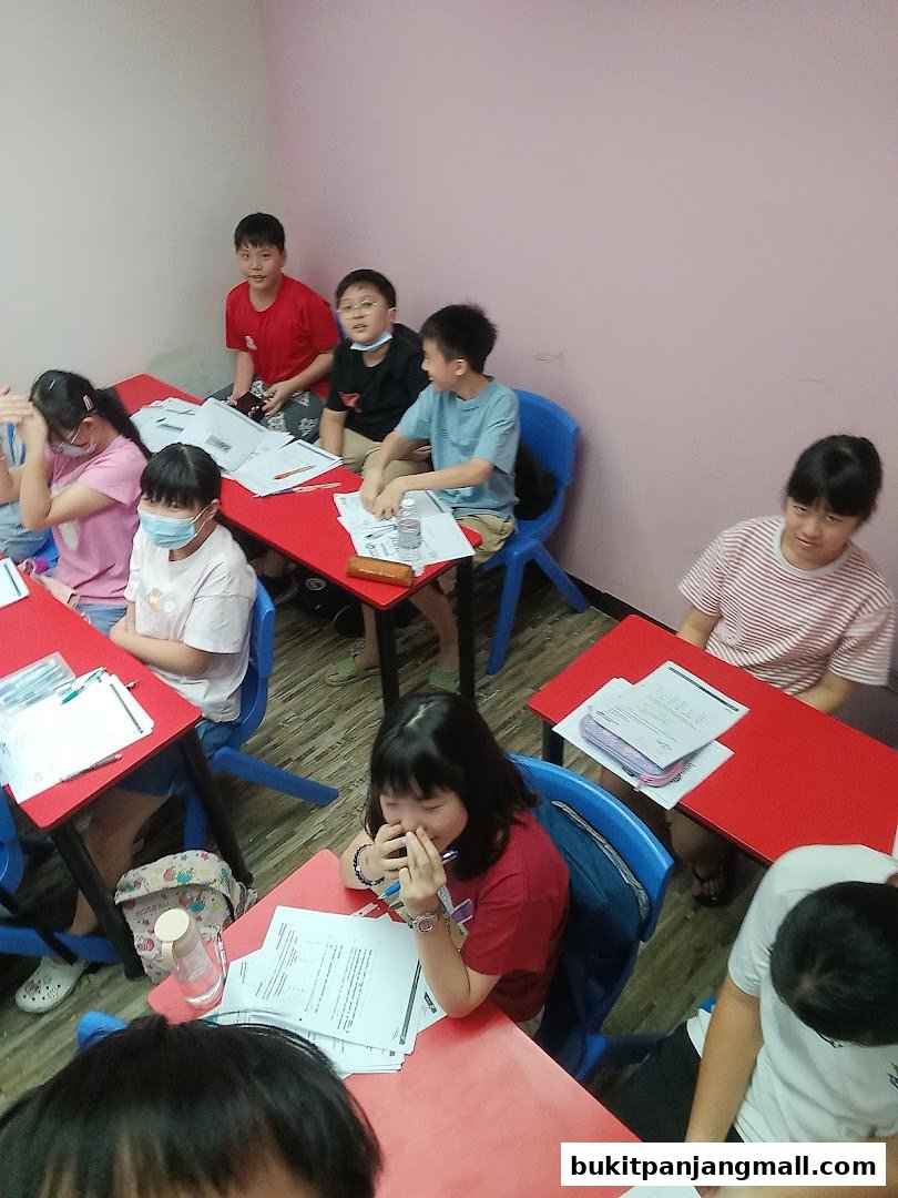 Students are seated at desks in a classroom setting, engaged in learning activities.