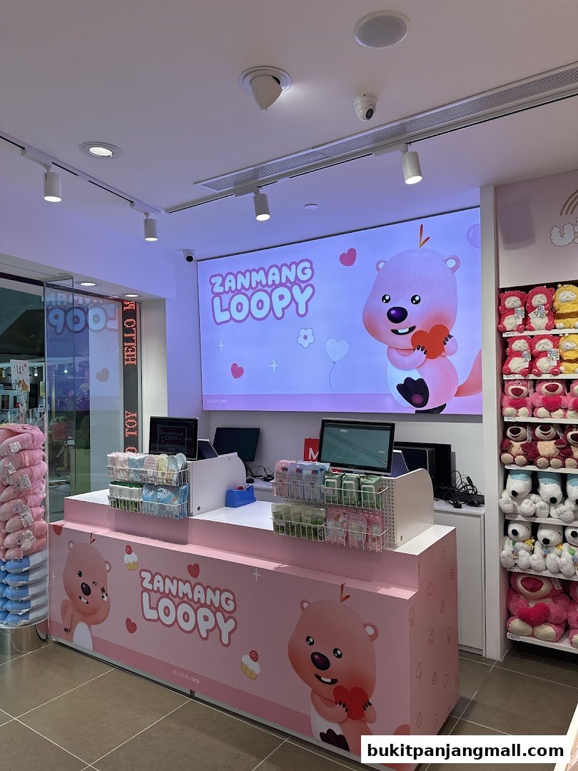 A brightly lit shop interior featuring a pink counter with "ZANMANG LOOPY" branding and plush toys on display.