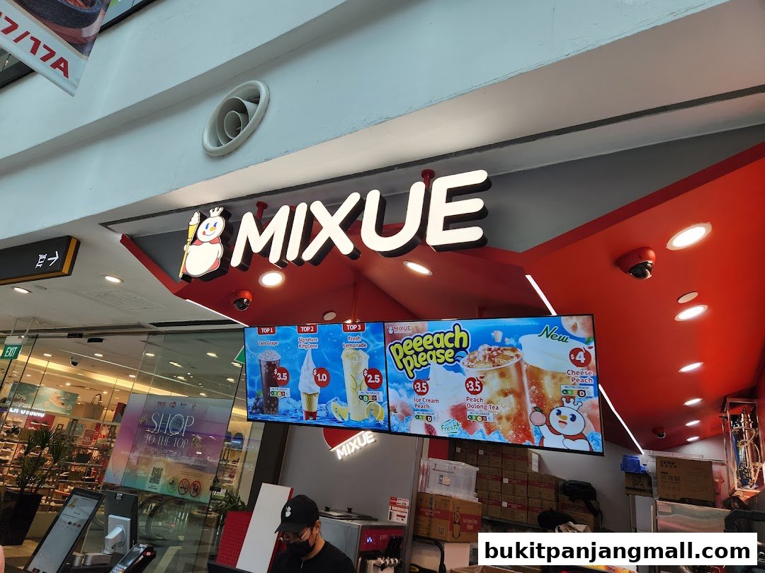The MIXUE shop front with illuminated signage and a digital menu displaying drinks and ice cream.