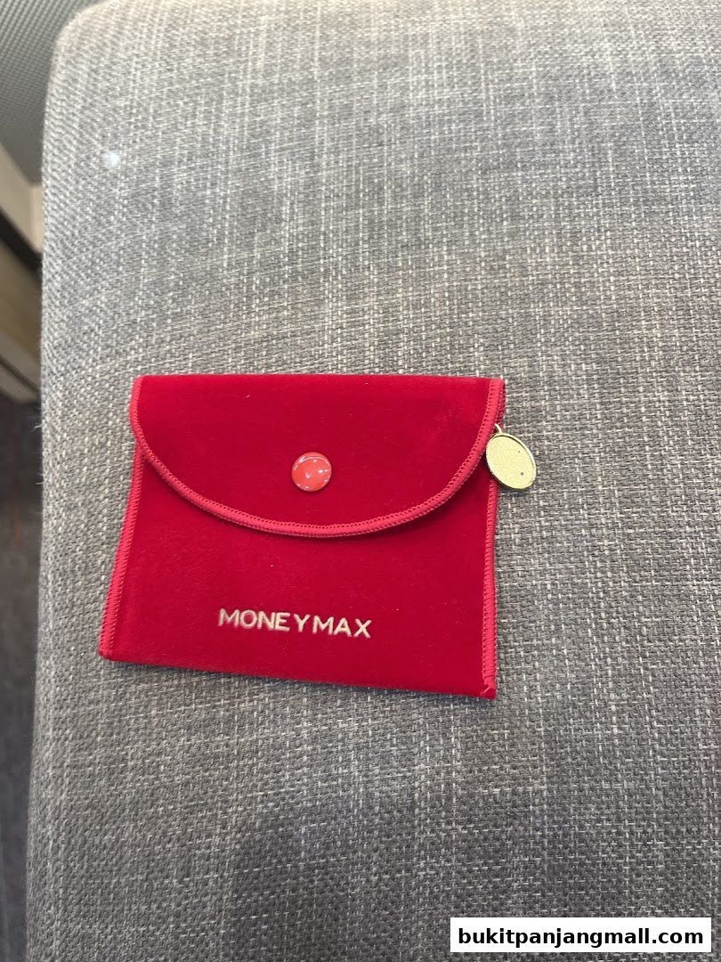 A red velvet pouch with the MoneyMax logo and a small charm.