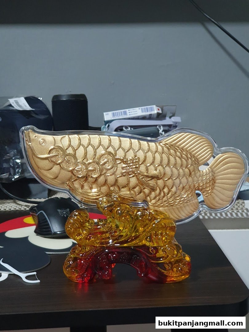 A golden Arowana fish figurine with a crystal base, symbolizing prosperity.