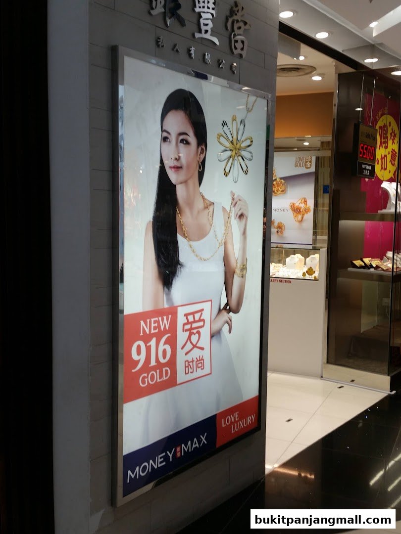 A large illuminated advertisement for MoneyMax Pawnshop featuring a model wearing gold jewelry.