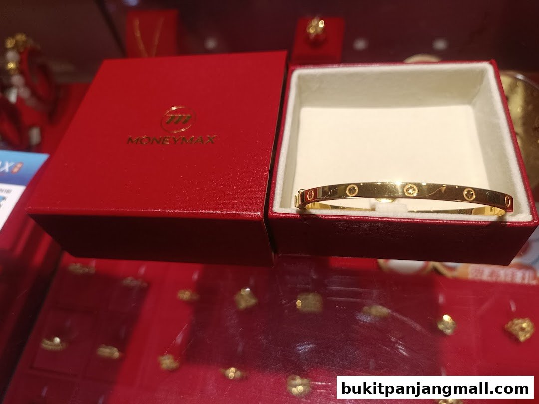 A gold bracelet with circular motifs displayed in a red jewelry box.