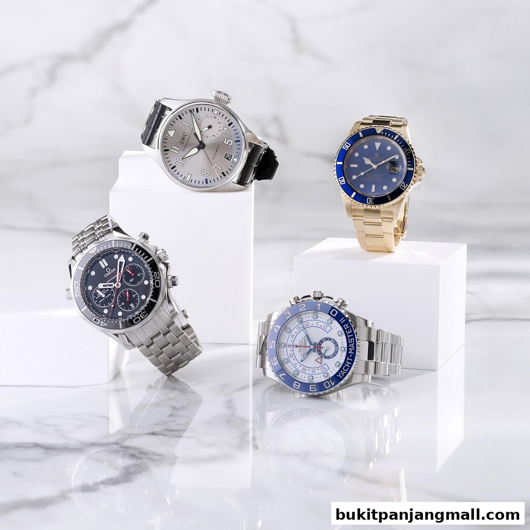 A collection of four luxury watches displayed on white pedestals against a marble background.