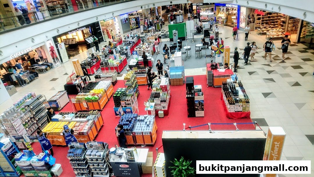 A bustling shopping mall interior with various retail displays and shoppers browsing.